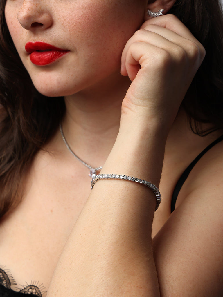 Woman wearing and showcasing a silver tennis bracelet