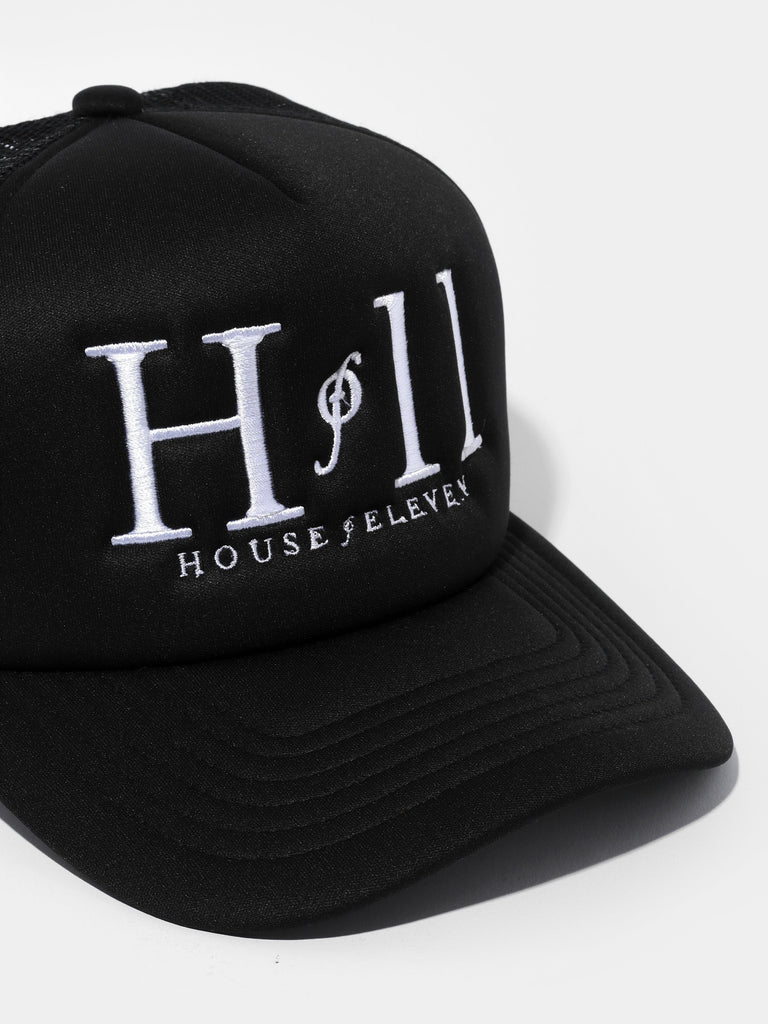 Product shot of a black flat top cap embroidered in white with House of Eleven logo