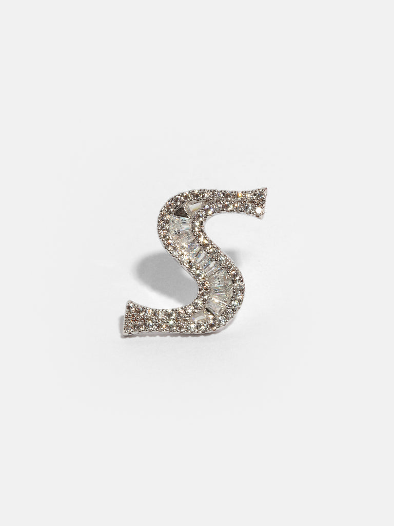 silver pin with S shaped front covered in small round and rectangle clear-colored gems