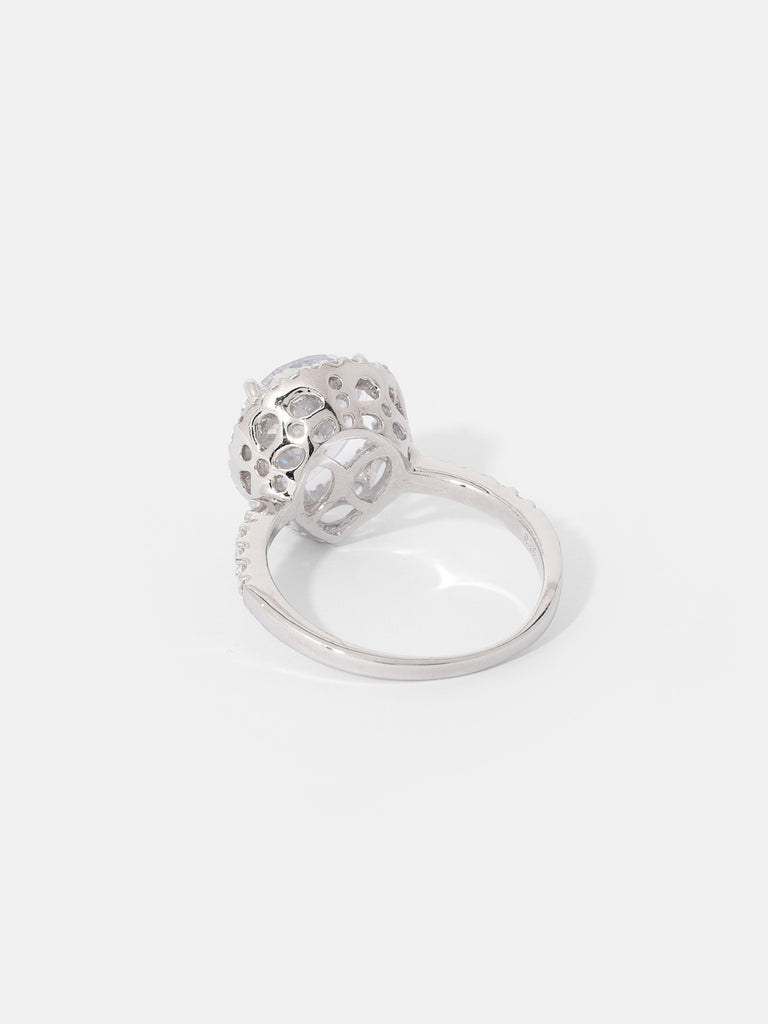 "Image description: A ring featuring a pear-cut center stone surrounded by a pavé set crystal halo. The ring is made of solid .925 sterling silver, is nickel-free, and rhodium plated. The center stone measures 10mm x 12mm in a pear shape, and the ring houses 27 brilliant-cut cubic zirconia stones, each measuring 1mm in diameter."