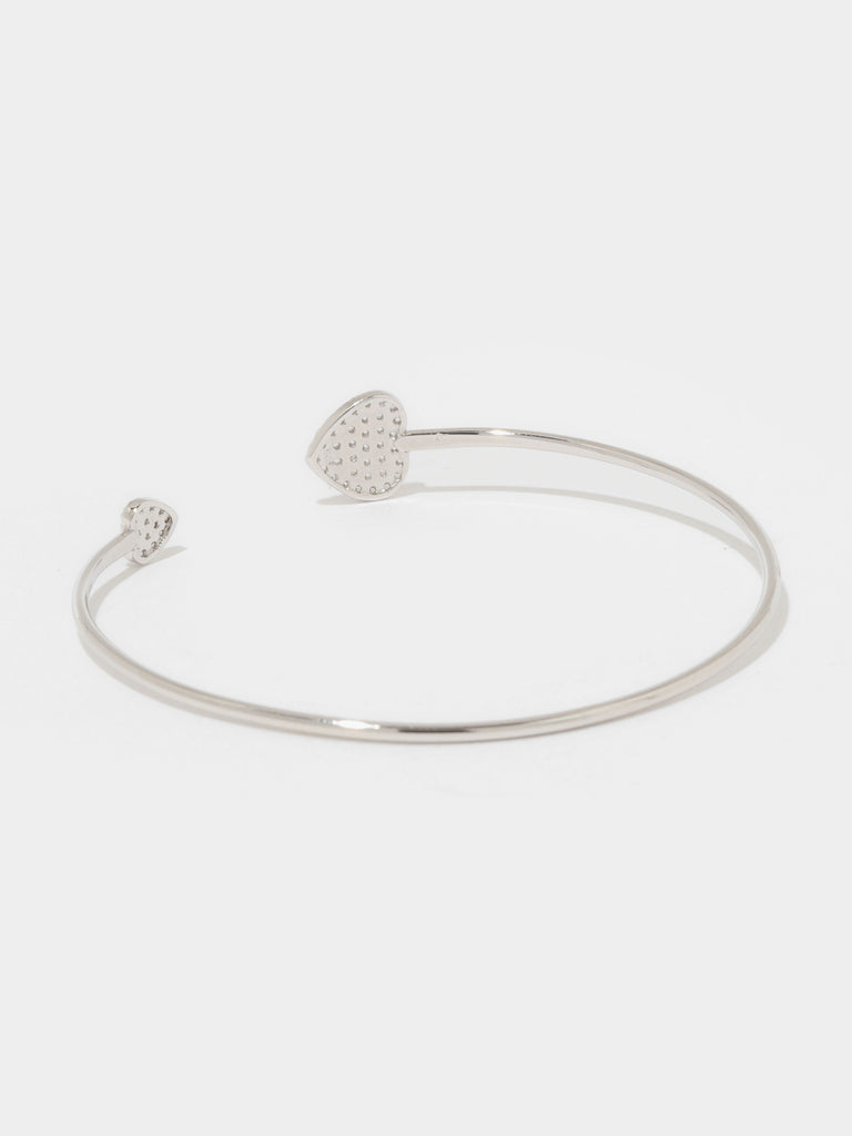 silver bangle bracelet with large and small hearts covered in small round clear-colored crystals on the the ends