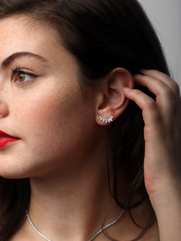 image of a woman wearing silver stud earrings with 6 clear marquise shaped gems