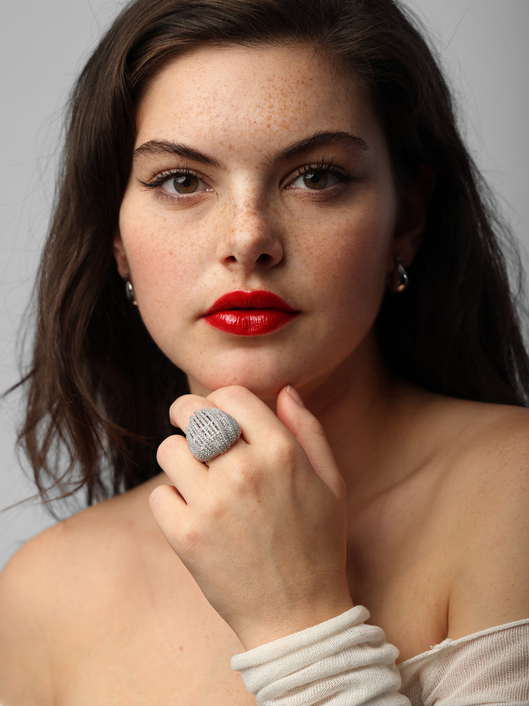 woman wearing dome shaped silver ring made of columns lined with small, round, clear-colored crystal gems