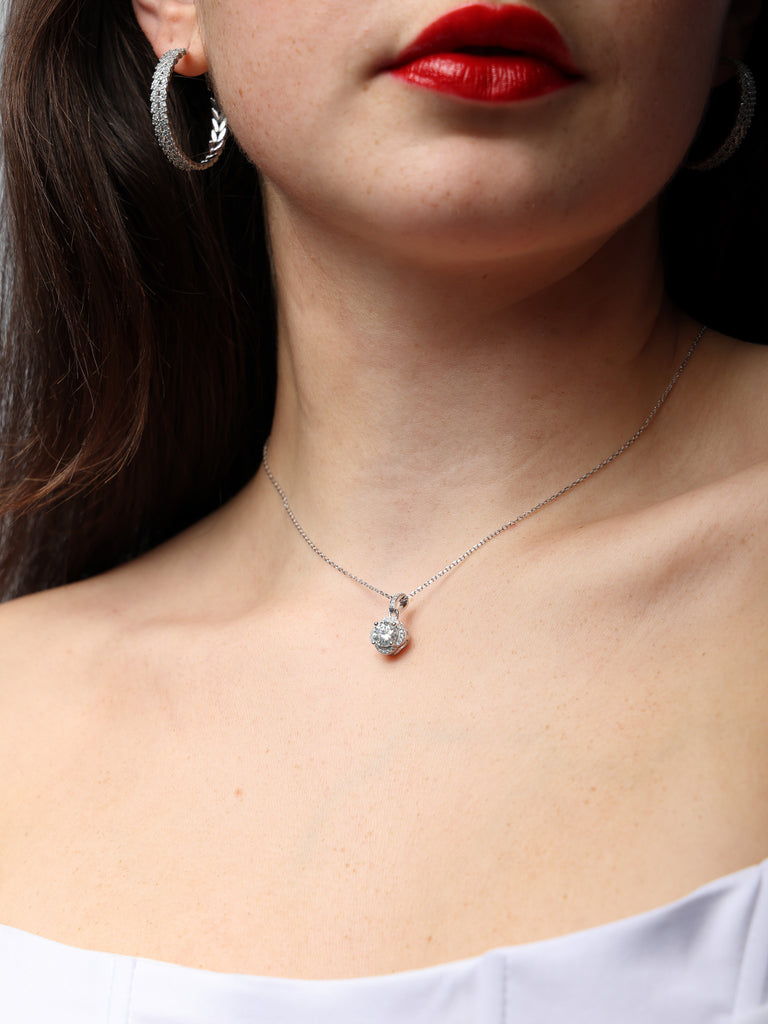 image of woman's neck wearing silver necklace with clear-colored, large, square shaped gem pendant outlined with small clear-colored crystals