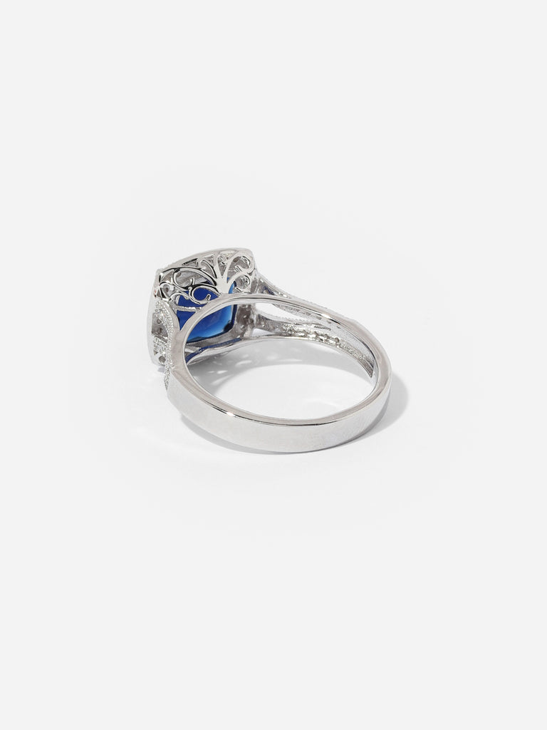 image of the back of Silver ring with large square shaped blue sapphire colored gem outlined with small clear crystals