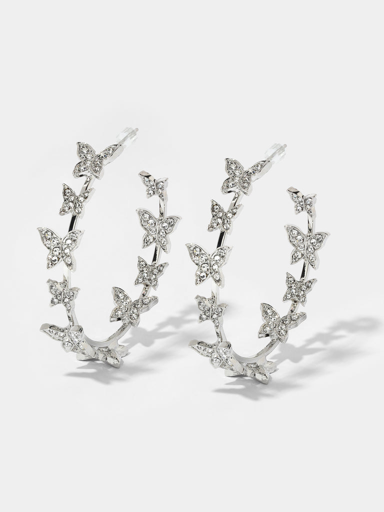 Image of silver hoops with 10 small butterfly motifs covered in clear-colored crystals 
