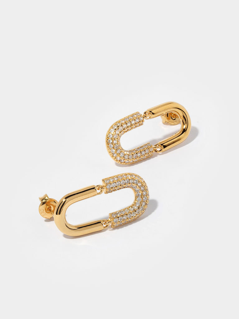 gold stud earrings in the shape of U link shape. Half of motif is covered in clear-colored crystals 