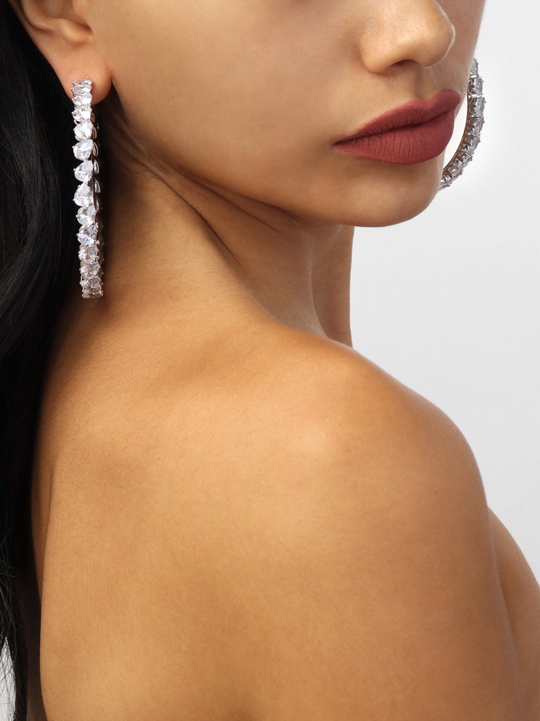 woman wearing silver hoops lined with pear shaped, clear-colored crystal gems