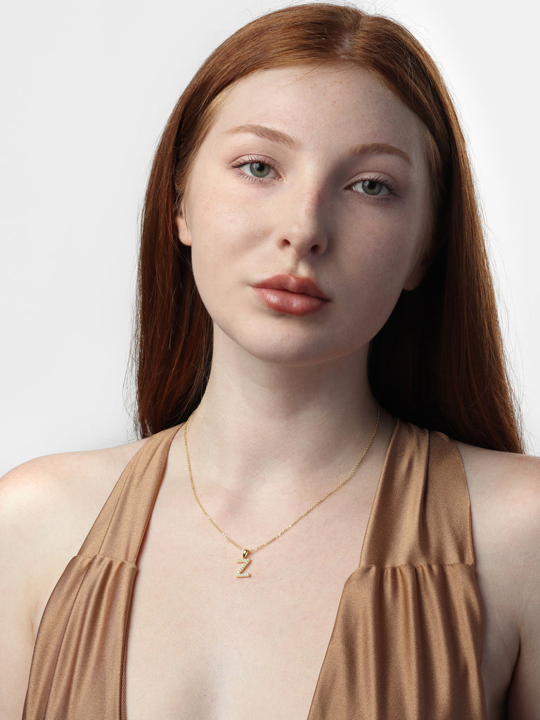 woman wearing gold necklace with a pendant in the shape of letter Z