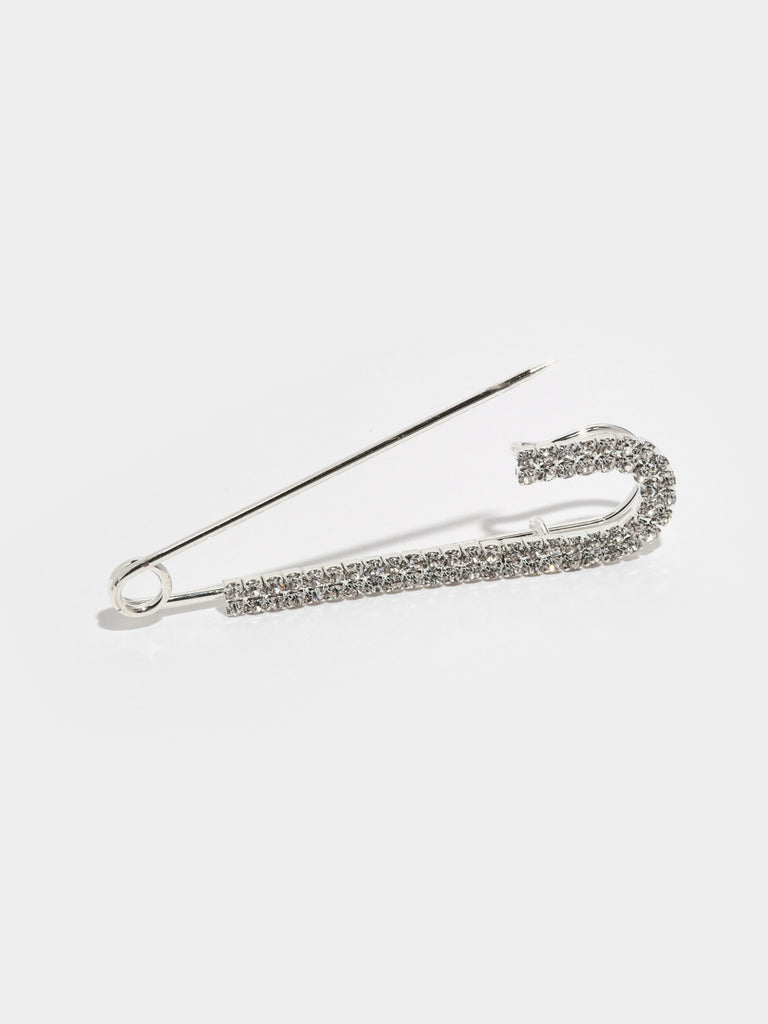 opened large silver safety pin with one side lined with small clear-colored crystal gems