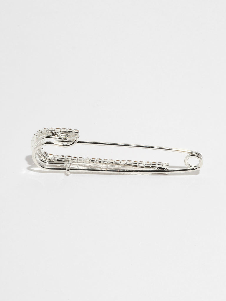 back of large silver safety pin with one side lined with small clear-colored crystal gems