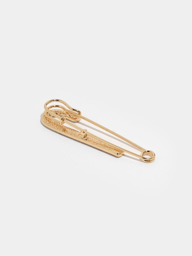 back of large gold safety pin with one side lined with small clear-colored crystal gems