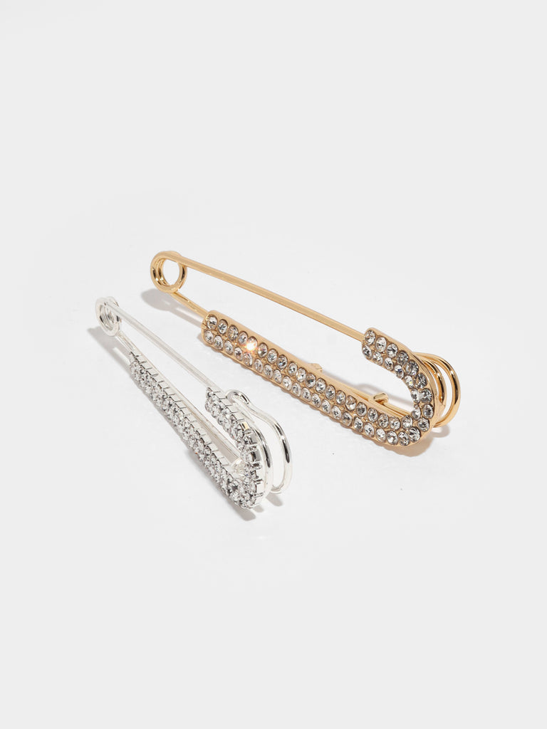 large gold and silver safety pins with one side lined with small clear-colored crystal gems