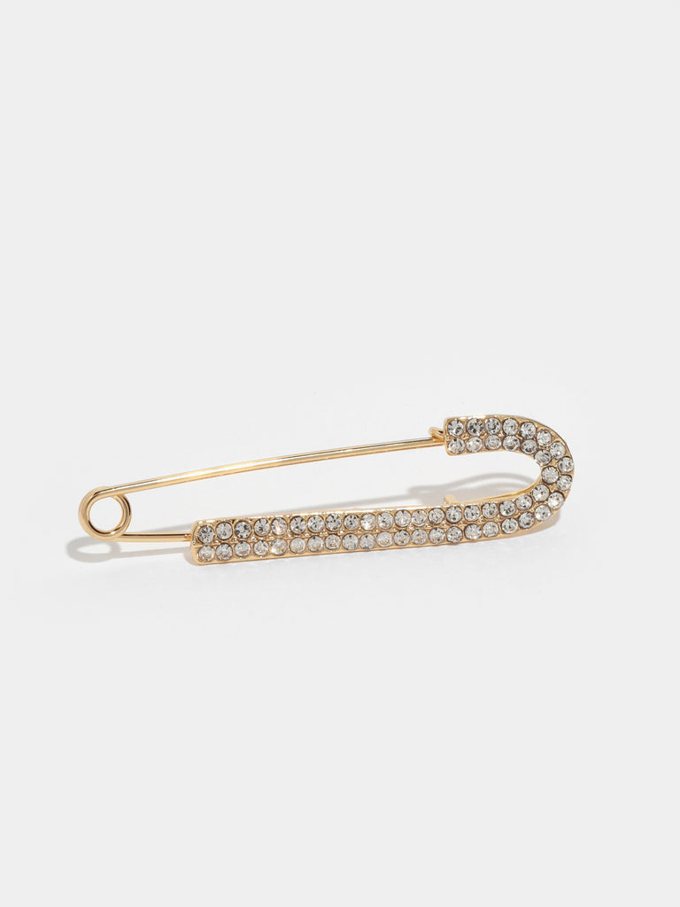 large gold safety pin with one side lined with small clear-colored crystal gems