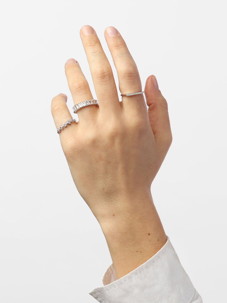 hand wearing silver ring with rectangular, clear-colored gems all around the band
