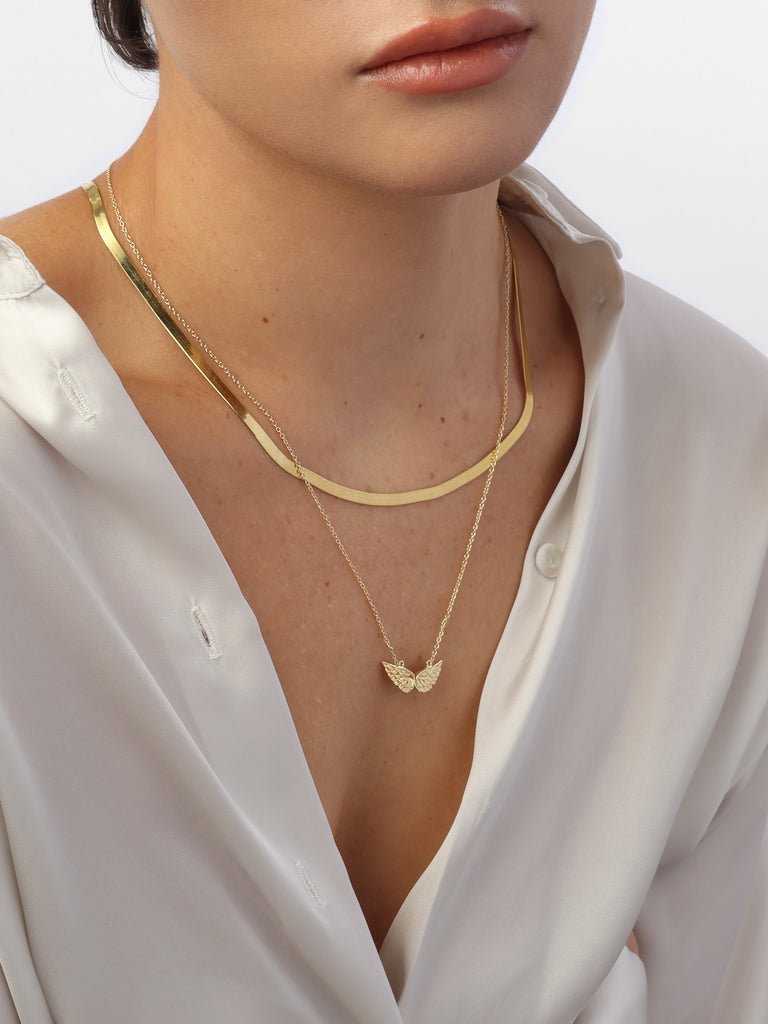 woman wearing gold necklace with angel wing motif pendant