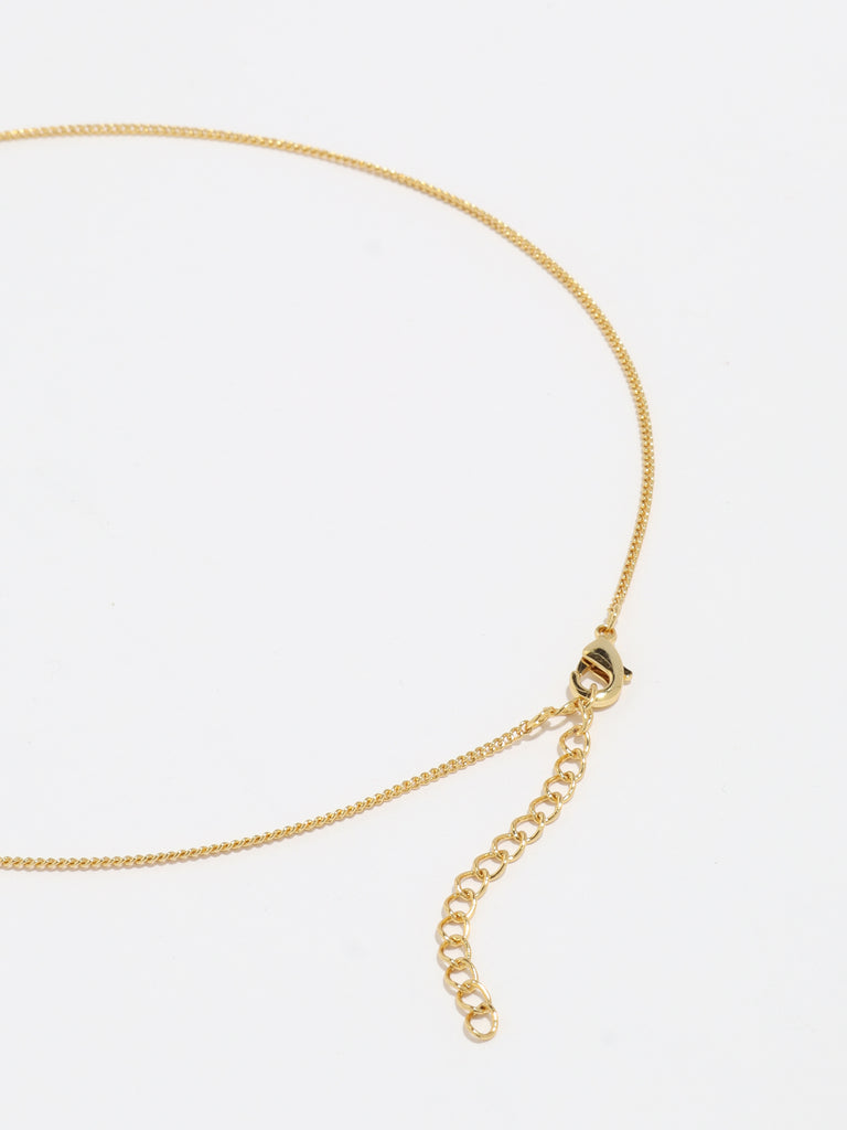 clasp of gold necklace with circle shaped pendant with House of eleven logo printed in the center