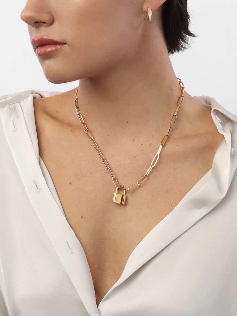 woman wearing gold necklace with link shaped chain and padlock shaped pendant 