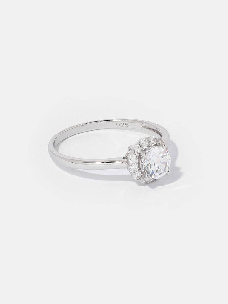 silver ring with large clear-colored crystal gem outlined by smaller clear-colored crystals 