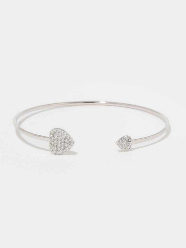 silver bangle bracelet with large and small hearts covered in small round clear-colored crystals on the the ends 