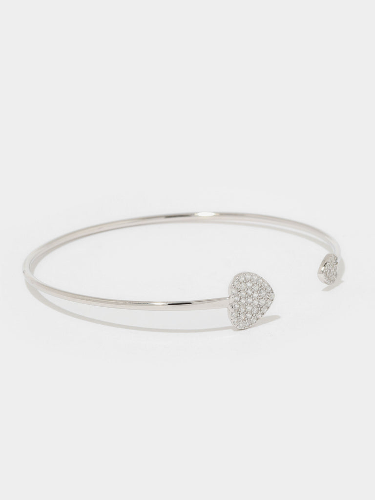 silver bangle bracelet with large and small hearts covered in small round clear-colored crystals on the the ends