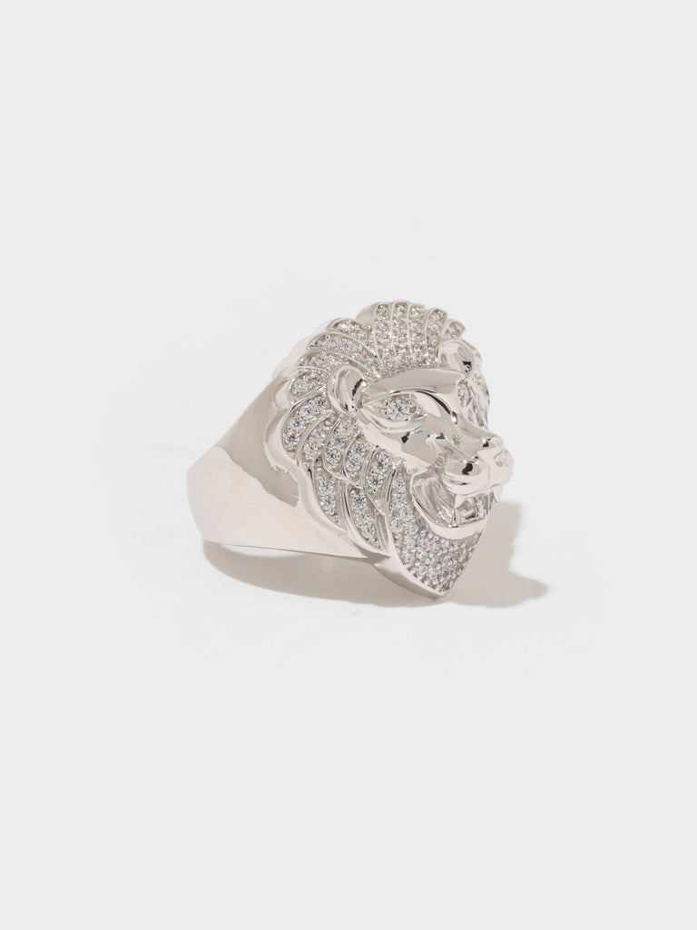 silver ring lion head shaped head in center and small clear-colored crystals adorning it's mane and eyes