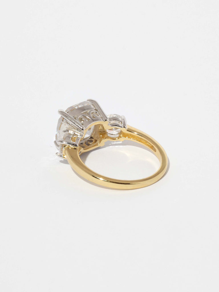 gold ring with large, square shaped, clear crystal gem in the center and smaller round clear gems on each side