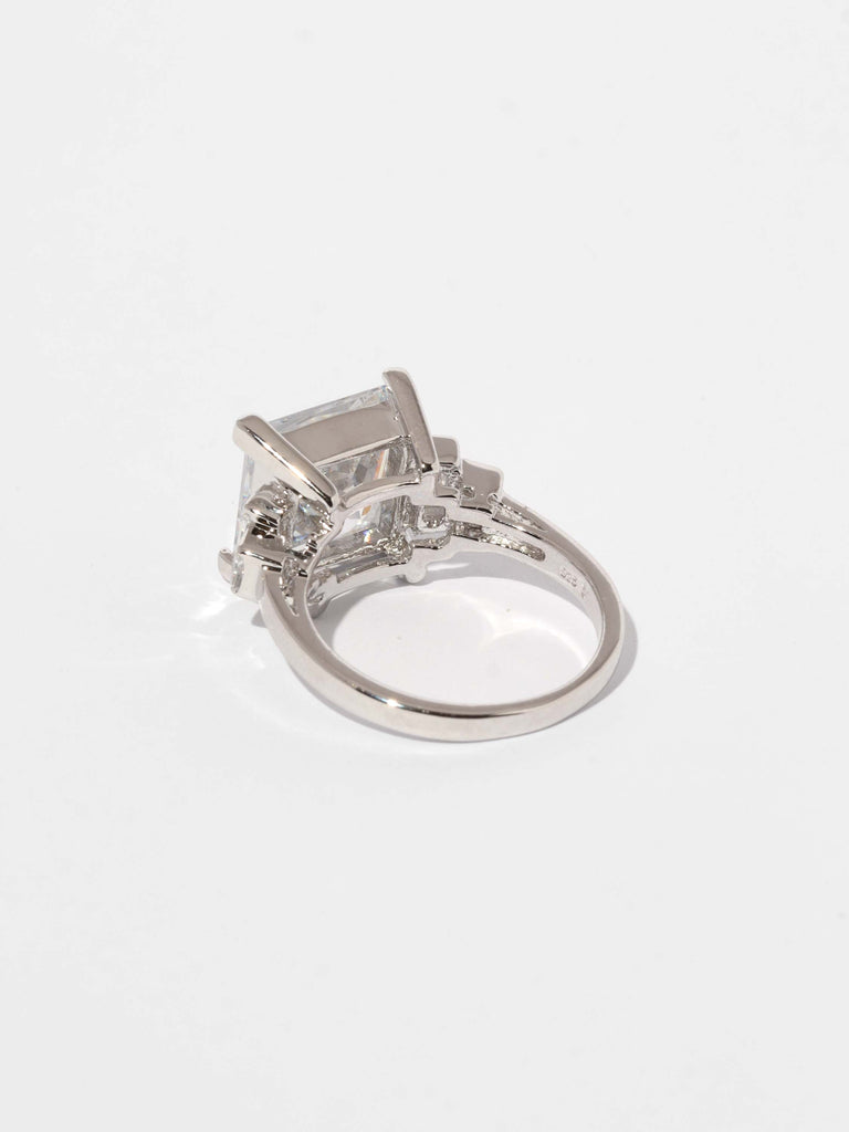 back of silver ring with large square shaped, clear-colored gem in the center and two smaller square shaped gems on each side