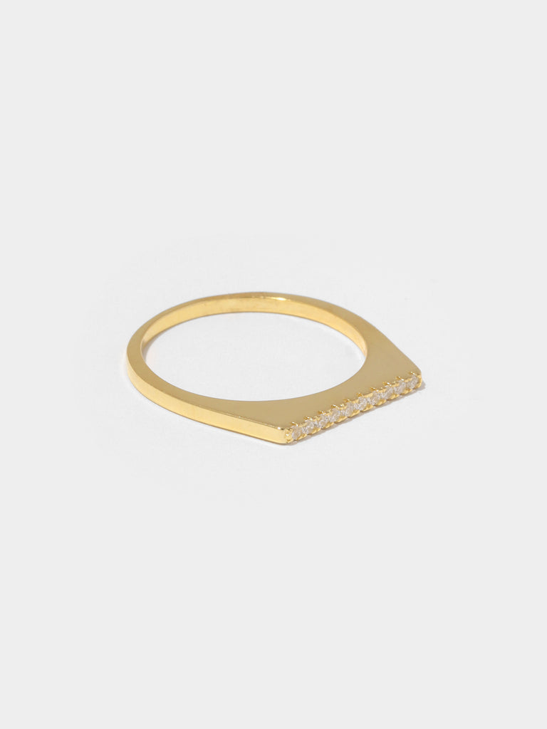 gold flat shape ring lined with small round clear-colored crystals on the top