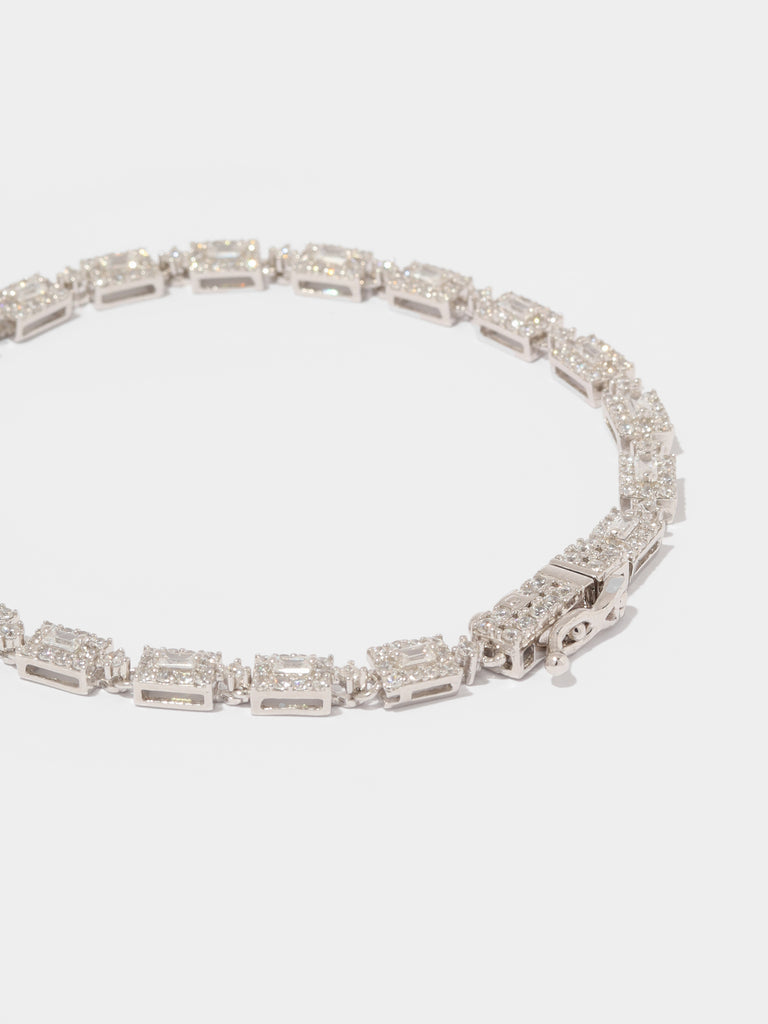 silver bracelet with rectangular link motif. In the center is a rectangle shaped, clear-colored gem outlined by small round clear-colored crystals