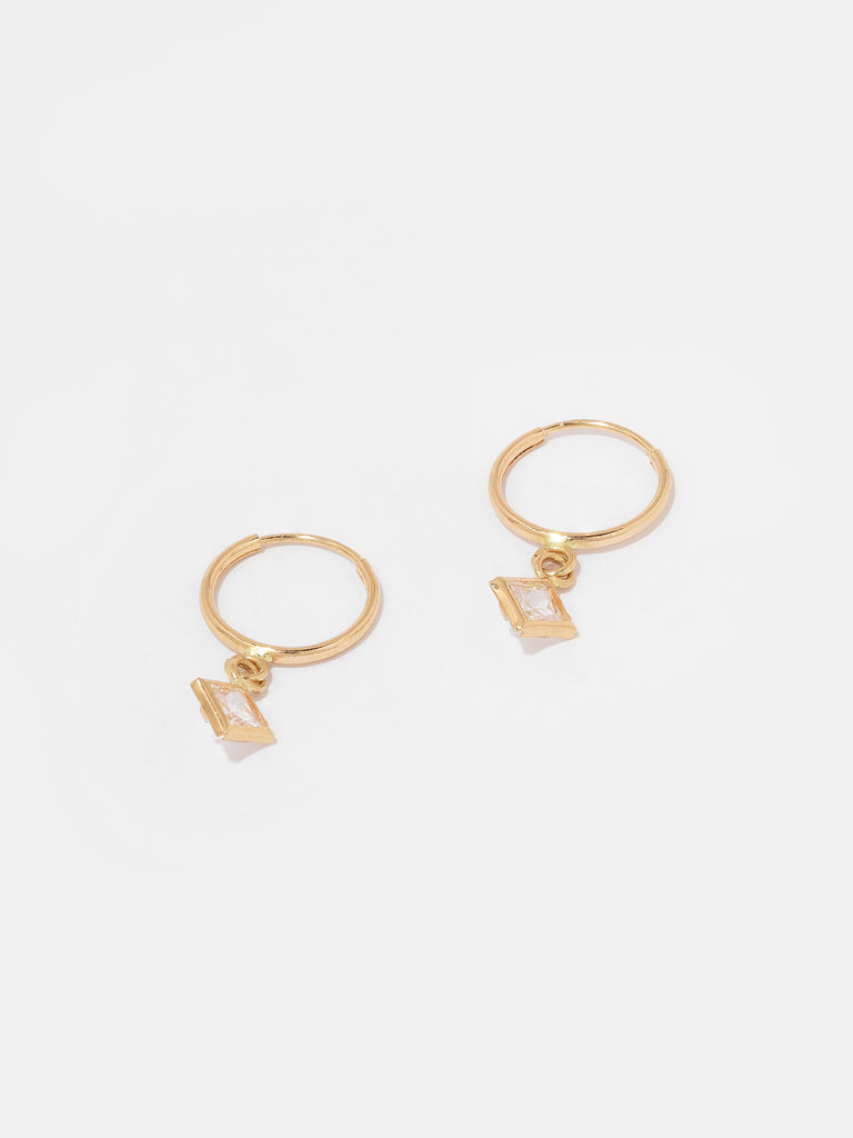 "Image description: A pair of earrings featuring square drop pendant crystals housed in mini solid 14K yellow gold hoops designed to dangle and sparkle with subtle movements. Each earring consists of 14K solid yellow gold with a square-cut cubic zirconia stone. The hoop measures 11.6mm in diameter, and the stone measures 5.7mm in width."